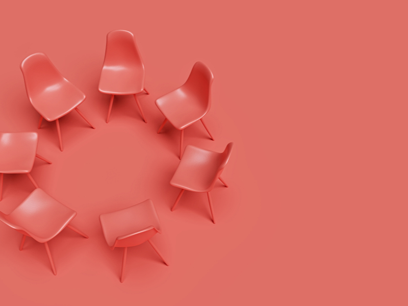 Circle of pink plastic chairs against a solid block pink background