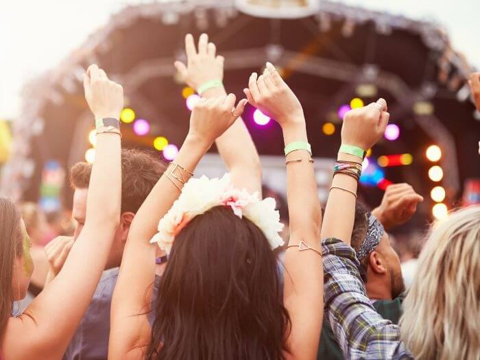 A crowd with their hands raised at a music festival.