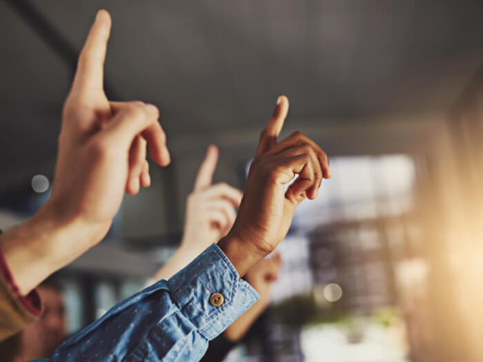 Numerous hands raised as if in support of a motion.