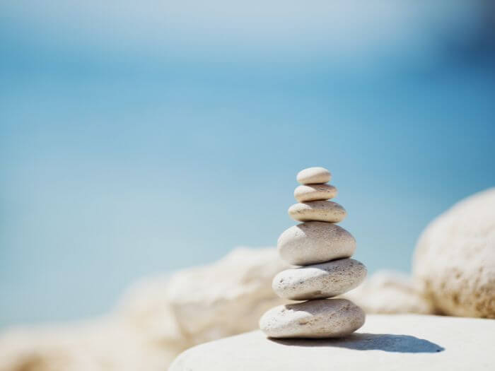 Stacked rocks on the shore against a clear blue sky.
