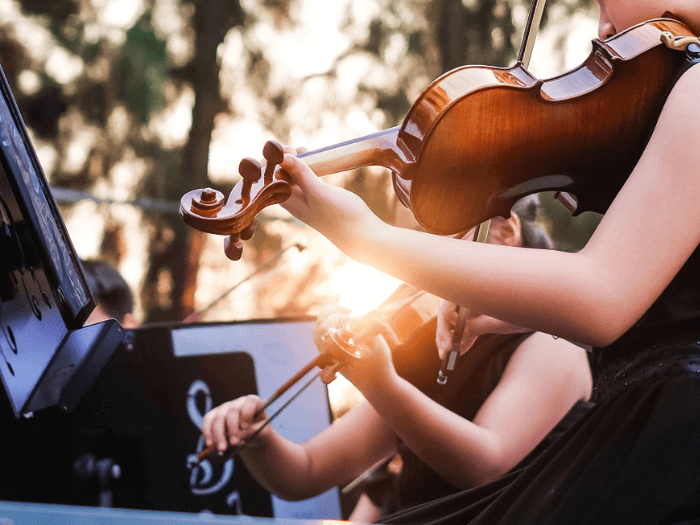 A closeup of two violinists playing as part of an orchestra.